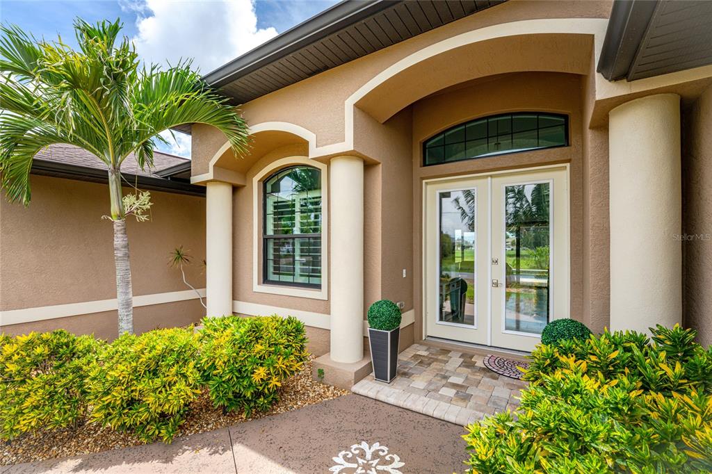 The exterior entrance features a double door, arched window, columns, and landscaped bushes — 4 WHITE MARSH LANE, ROTONDA WEST, FL
