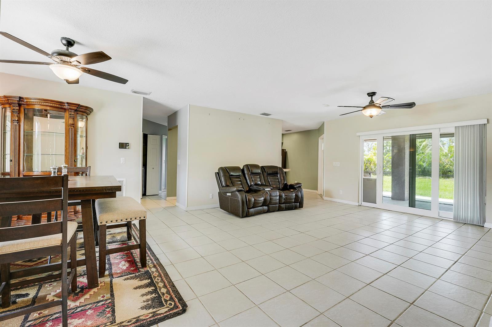 A spacious living and dining area features tile flooring, two ceiling fans, and sliding glass doors — 12628 N 70th Pl Place N, FL 33412, FL