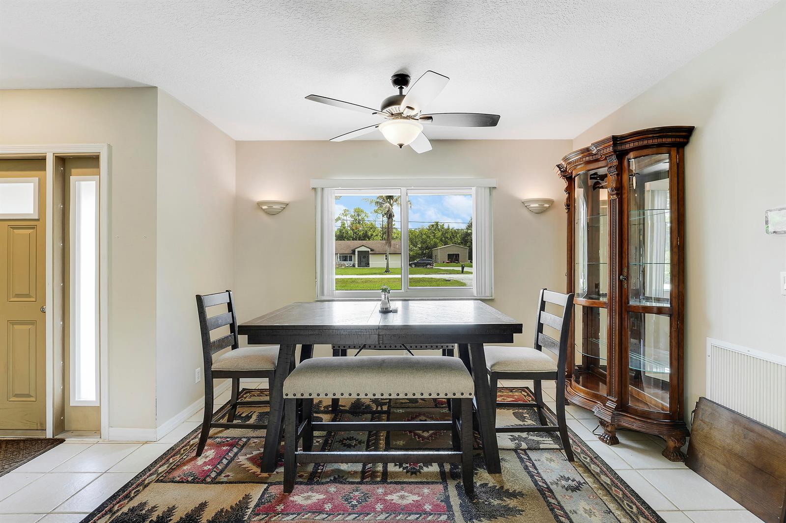 A dining area features a dark wood table, chairs, a bench, and a china cabinet — 12628 N 70th Pl Place N, FL 33412, FL