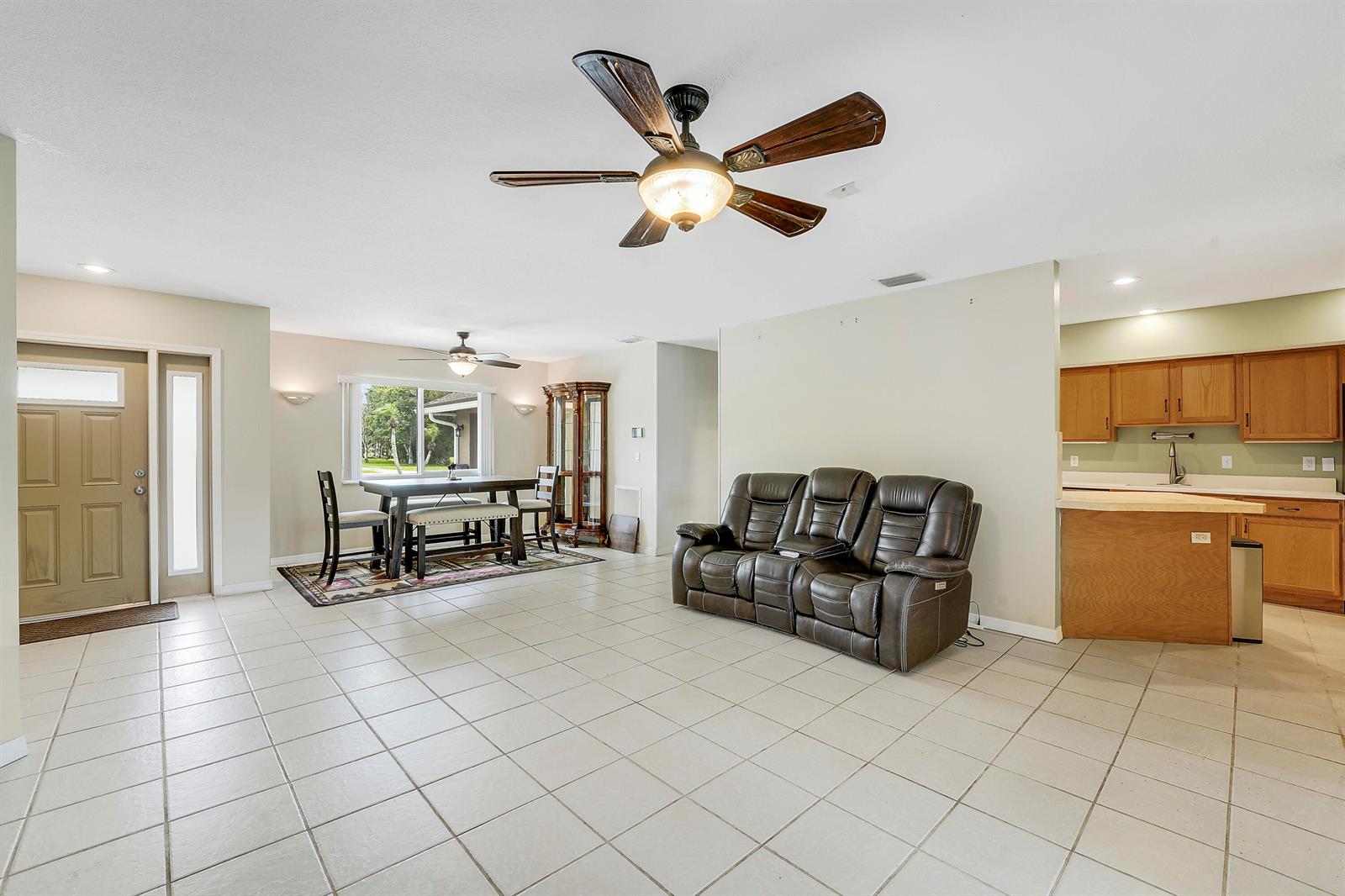 An open-concept living and dining area features tile flooring, a ceiling fan, and kitchen cabinetry — 12628 N 70th Pl Place N, FL 33412, FL