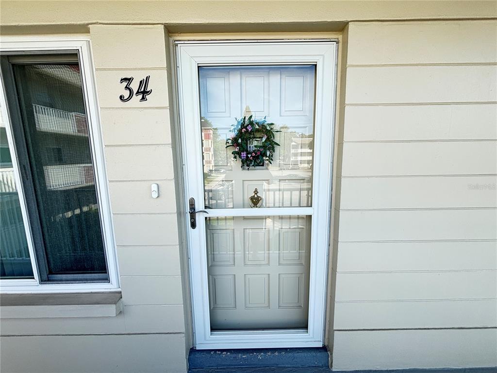 The exterior view shows a white front door with a storm door and number 34 — 2262 SWEDISH DR. UNIT 34, CLEARWATER, FL