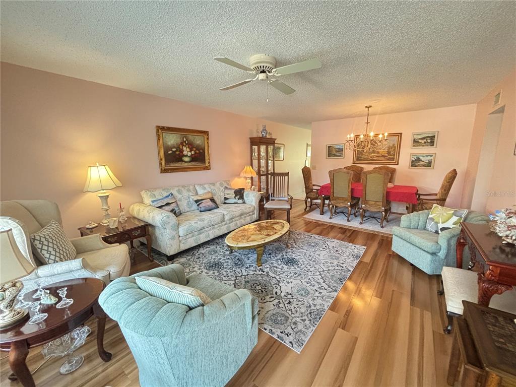 A living room and dining area feature hardwood floors, a patterned rug, and floral furniture — 2262 SWEDISH DR. UNIT 34, CLEARWATER, FL
