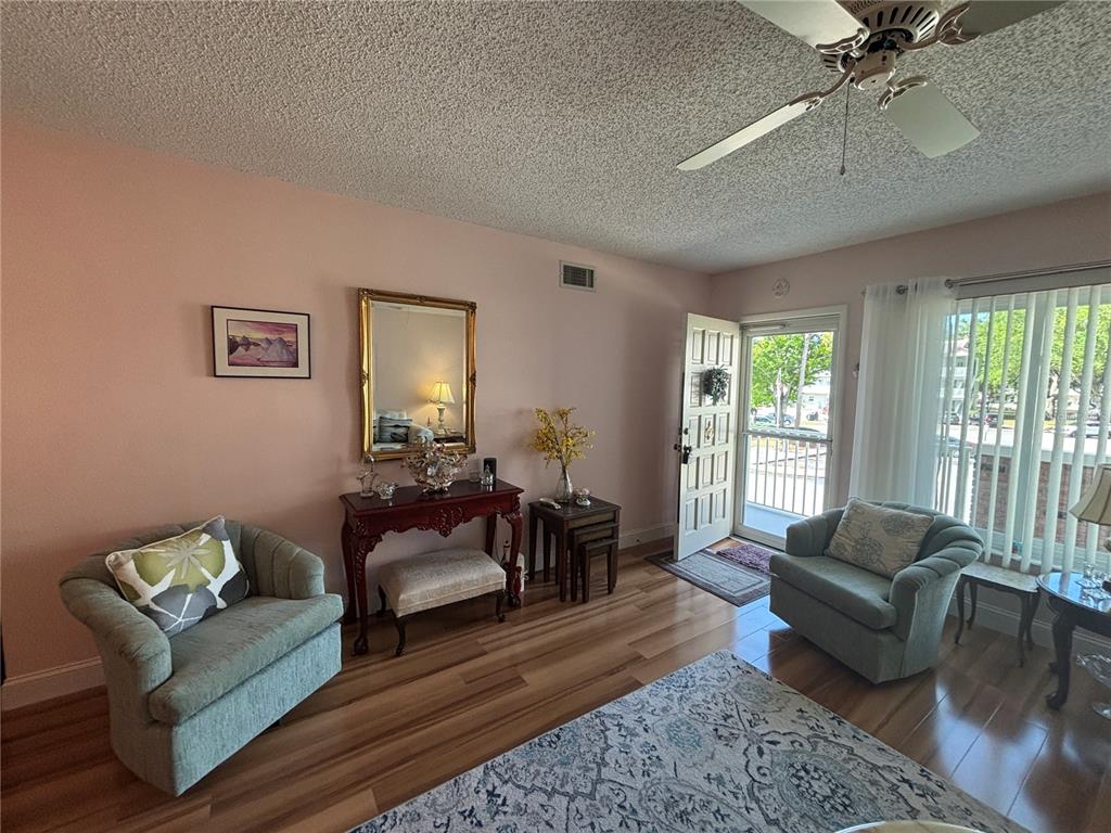 A living room features light pink walls, wood flooring, two armchairs, and a front door — 2262 SWEDISH DR. UNIT 34, CLEARWATER, FL