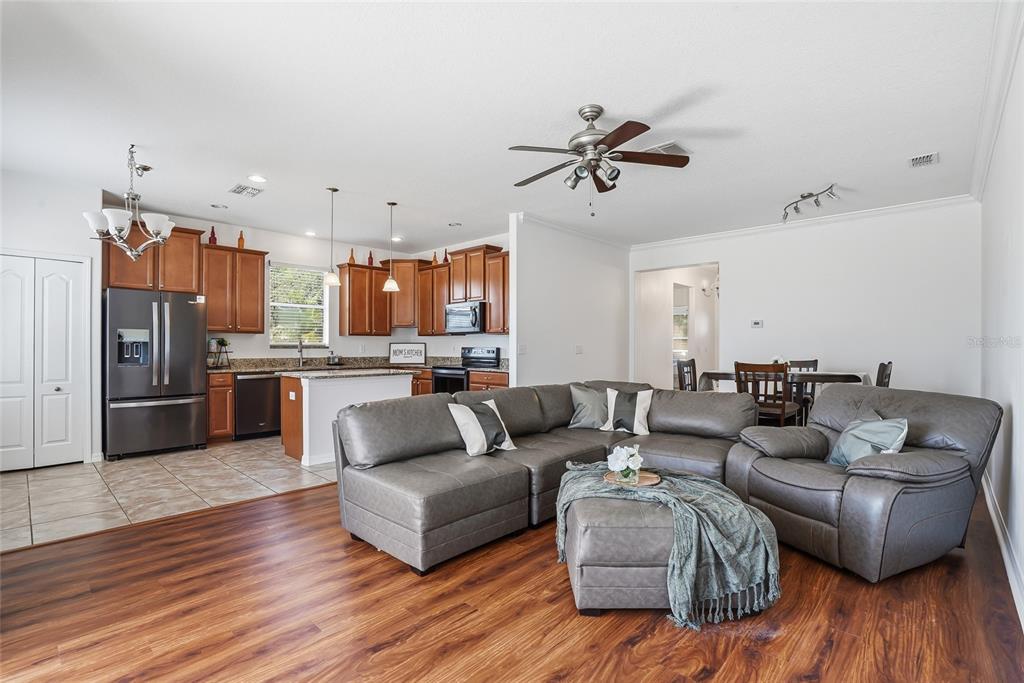 An open-concept living room and kitchen featuring wood-look flooring, a sectional sofa, and wood cabinetry — 2444 DAKOTA ROCK DRIVE, RUSKIN, FL