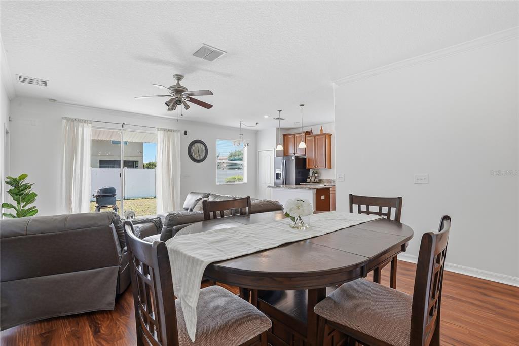 An open-concept living and dining area features wood-look flooring, a ceiling fan, and a kitchen — 2444 DAKOTA ROCK DRIVE, RUSKIN, FL