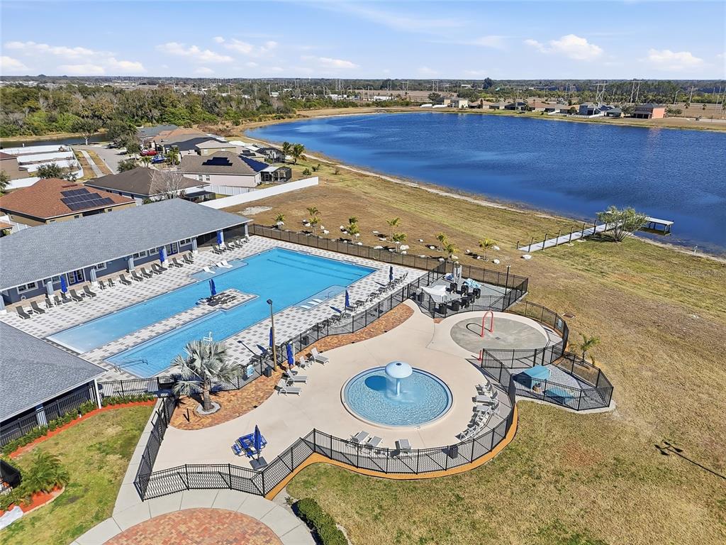 An aerial view shows a community swimming pool, a splash pad, and a lake — 2444 DAKOTA ROCK DRIVE, RUSKIN, FL