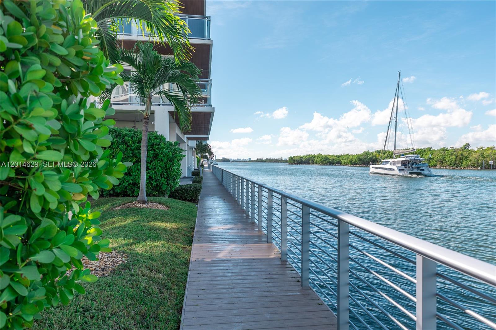 A wooden walkway runs alongside a modern building and a canal with a sailboat — 6100 N Ocean Dr # 3N, Hollywood FL 33019, HOLLYWOOD, FL