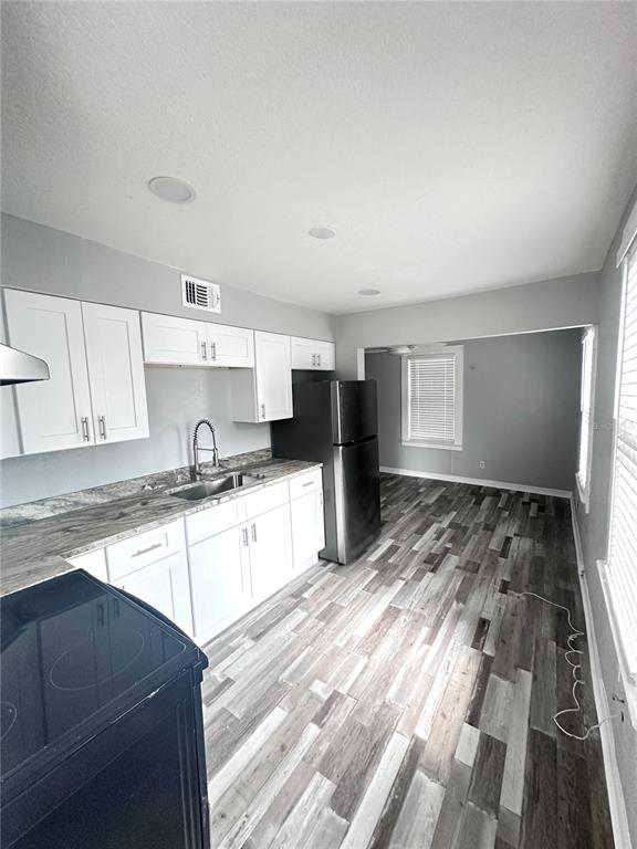 A kitchen features white cabinets, a stainless steel refrigerator, and wood-look flooring — 128 W NORTH STREET, TAMPA, FL