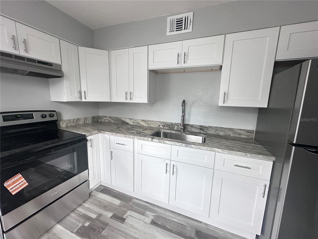 A kitchen features white shaker cabinets, stainless steel appliances, and gray faux-marble countertops — 128 W NORTH STREET, TAMPA, FL