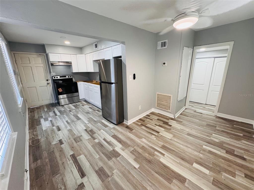 A kitchen with white cabinets, stainless steel appliances, and wood-look flooring — 128 W NORTH STREET, TAMPA, FL