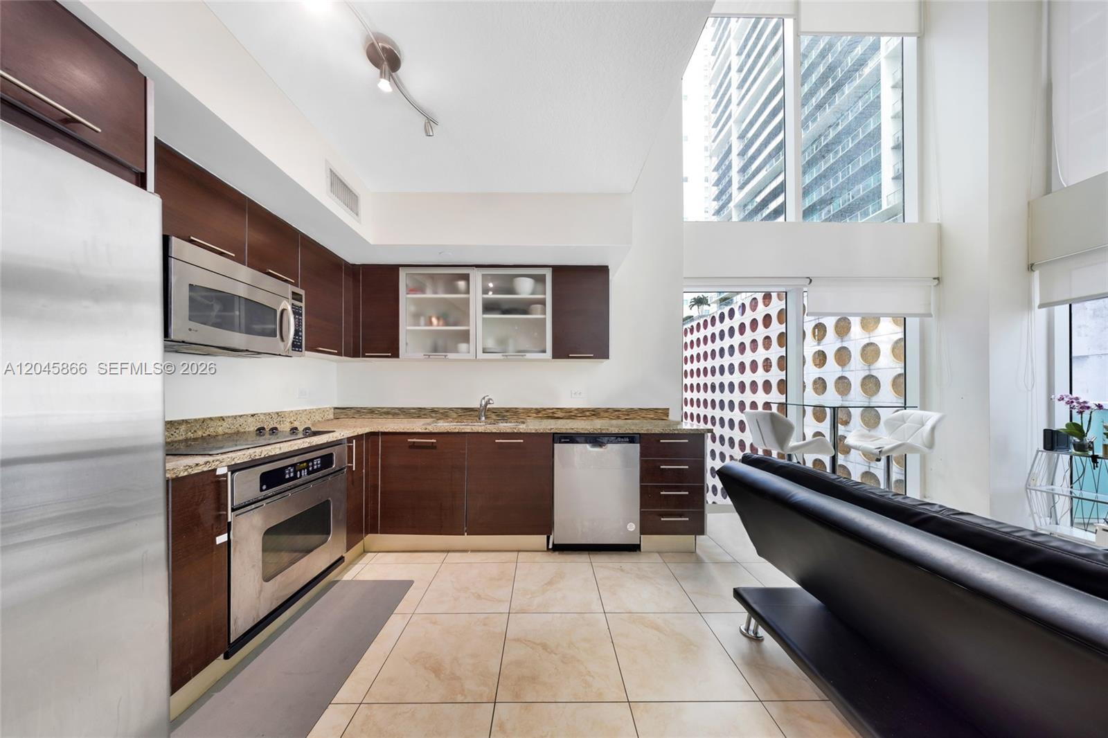 A modern kitchen features dark wood cabinets, stainless steel appliances, and floor-to-ceiling windows — 41 SE 5th St # 502, Miami FL 33131, MIAMI, FL