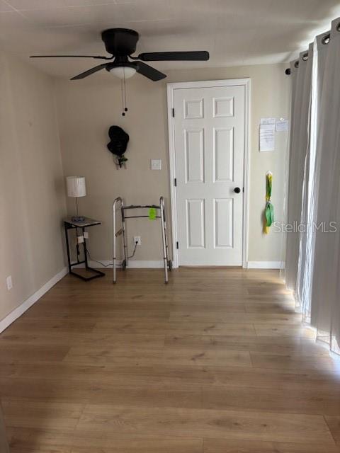 A room with light wood-look flooring, a ceiling fan, a white door, and a walker — 9145 RALLY LANE, HOLIDAY, FL
