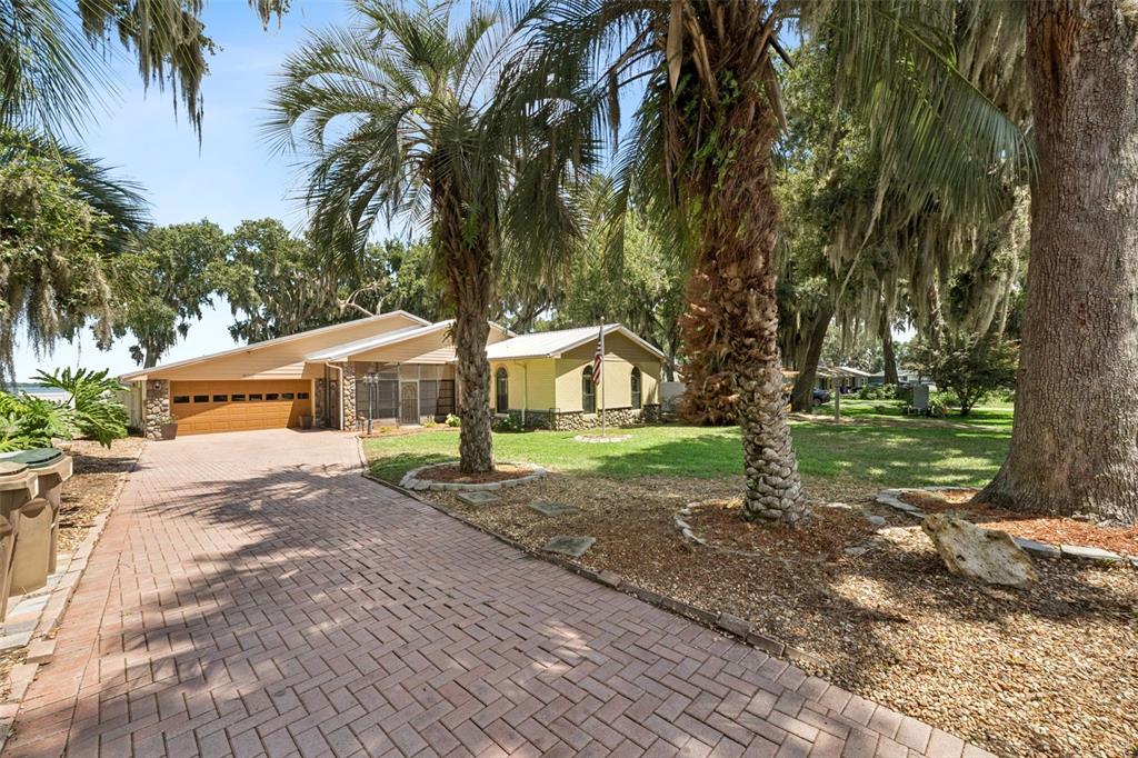 A single-story house with a brick driveway, palm trees, and a two-car garage — 35040 SHADY OAKS LANE, FRUITLAND PARK, FL