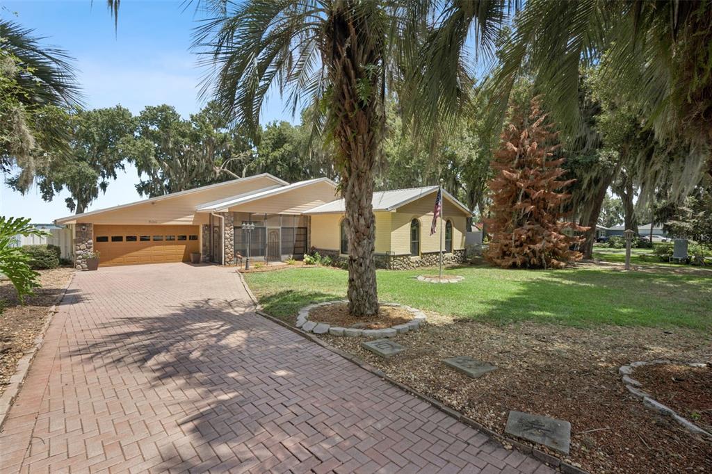 A single-story house with a brick driveway, stone accents, and a large palm tree — 35040 SHADY OAKS LANE, FRUITLAND PARK, FL