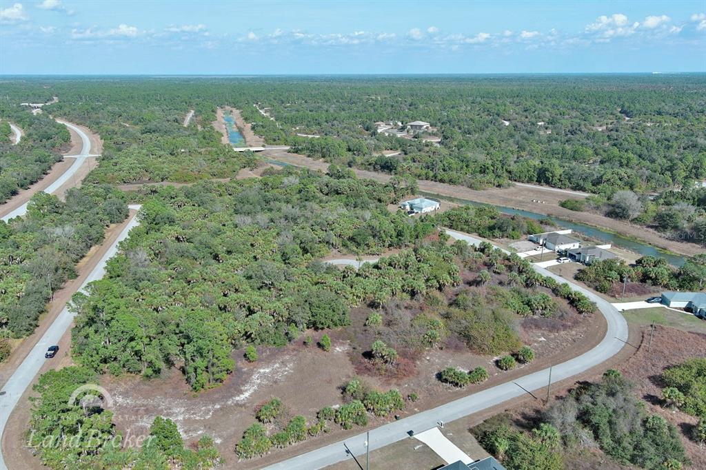 An aerial view shows a paved road curving through a wooded area with scattered houses — EASTMAN CIRCLE, NORTH PORT, FL