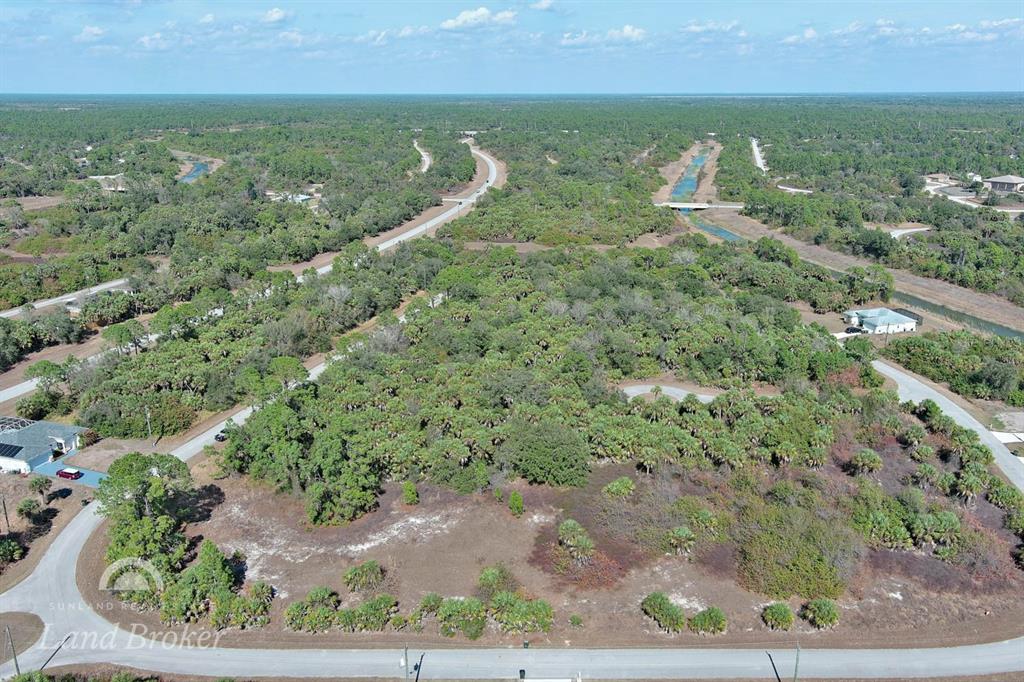 An aerial view shows a vacant, wooded residential lot bordered by paved roads and canals — EASTMAN CIRCLE, NORTH PORT, FL