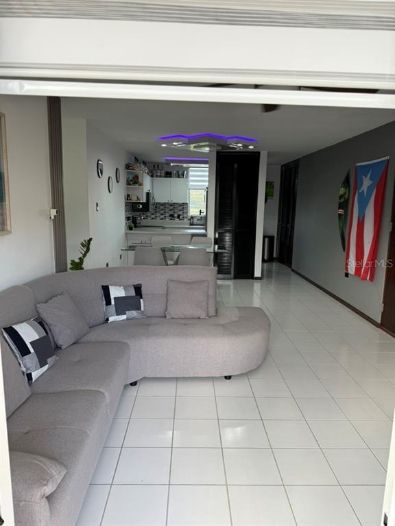 A living room with a gray sectional sofa, white tile floors, and an open kitchen — Codominium VISTA REAL UNIT 9, FAJARDO, PR