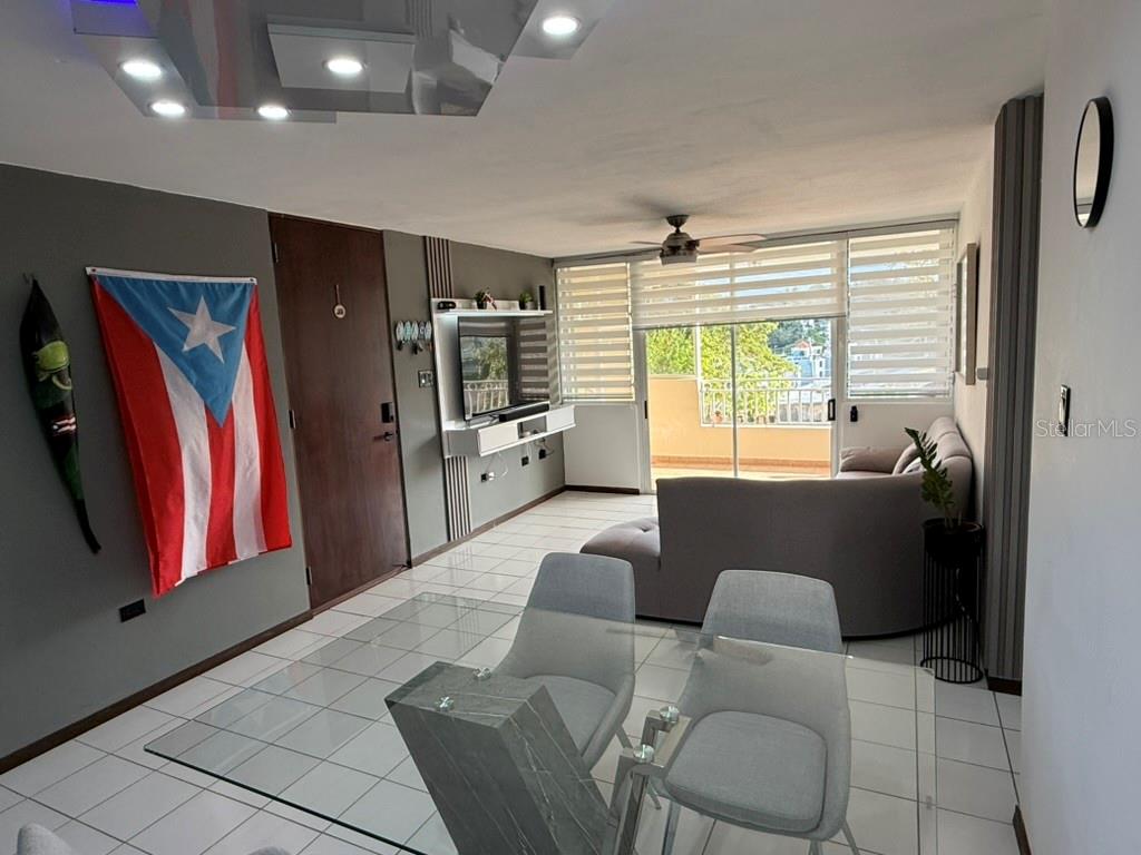 A living and dining area with a glass table, grey sofa, and a Puerto Rican flag — Codominium VISTA REAL UNIT 9, FAJARDO, PR