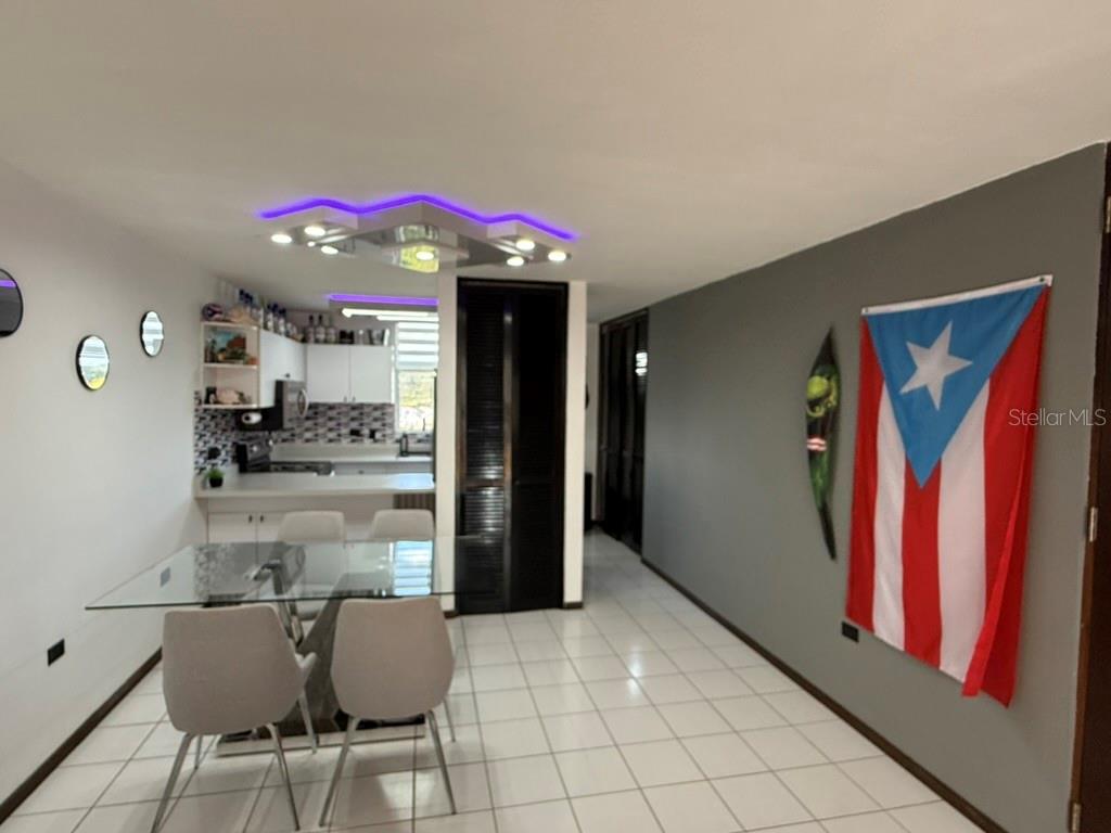 A dining area with a glass table, modern chairs, and a Puerto Rican flag on display — Codominium VISTA REAL UNIT 9, FAJARDO, PR