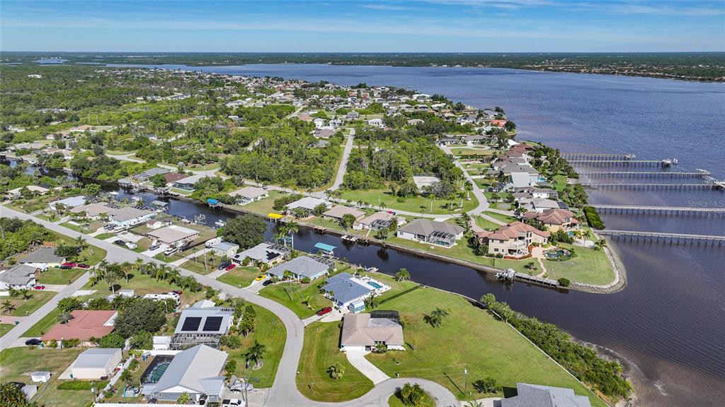 An aerial view shows waterfront homes along a canal leading to a large body of water — 3522 FOX TERRACE, PORT CHARLOTTE, FL