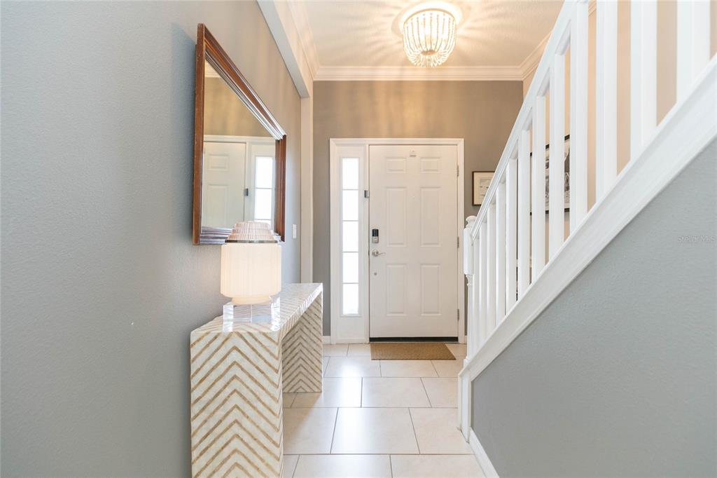 A bright entryway features a chevron-patterned console table, a wall mirror, and a staircase — 4052 70TH TERRACE N, PINELLAS PARK, FL