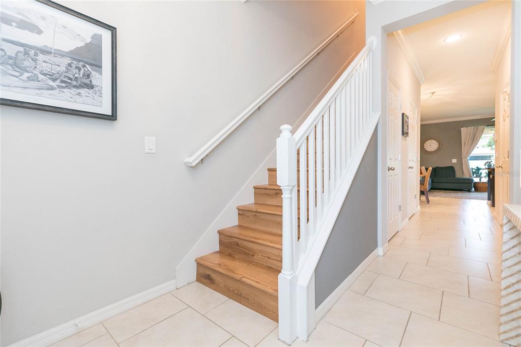 A staircase with wooden treads and white railings sits in a tiled entryway — 4052 70TH TERRACE N, PINELLAS PARK, FL