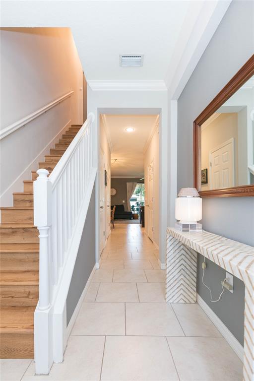 An entryway features a wooden staircase, tiled flooring, a console table, and a hallway view — 4052 70TH TERRACE N, PINELLAS PARK, FL