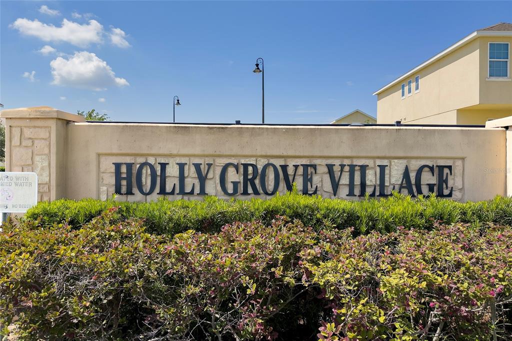 A stone monument sign for Holly Grove Village stands in front of a residential building — 129 HOLLY VILLAGE DRIVE, DAVENPORT, FL