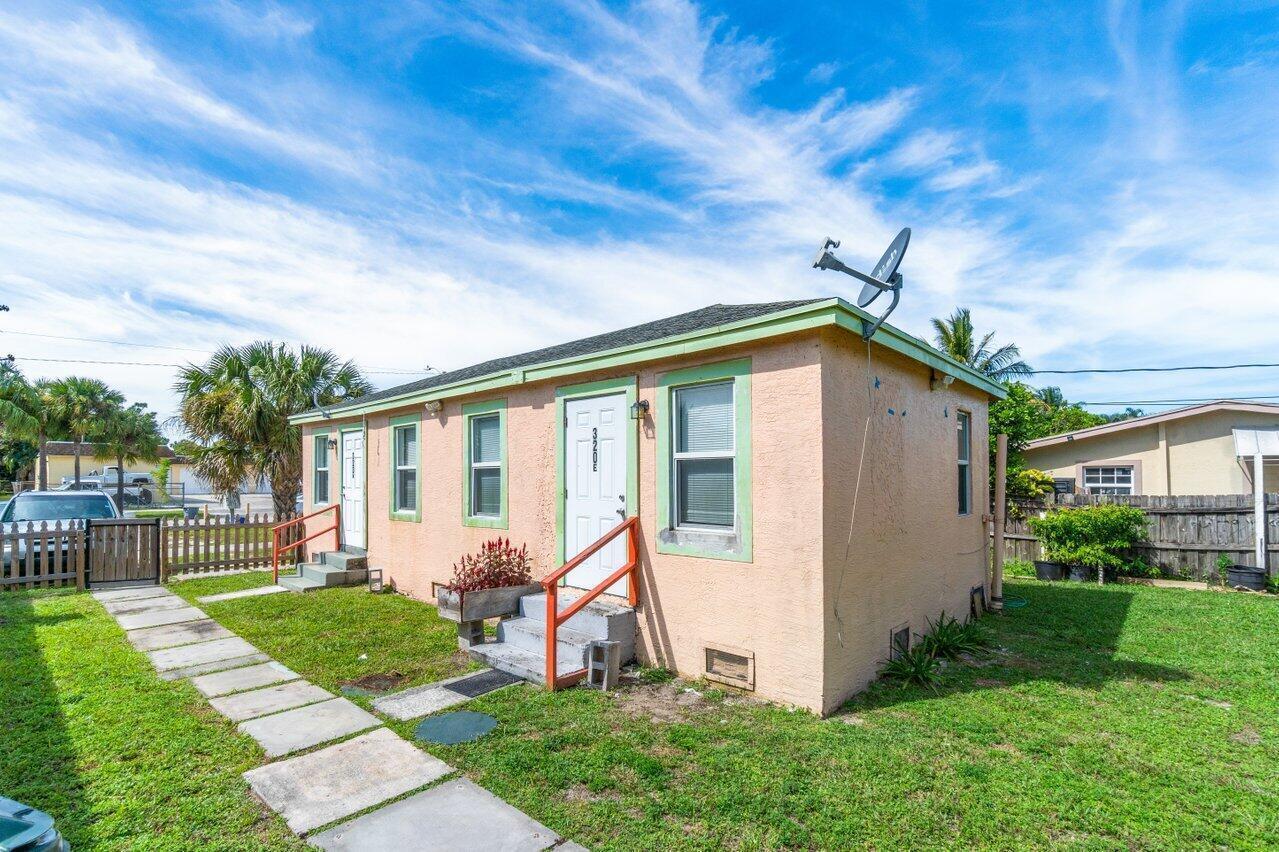 A single-story peach-colored house with a green trim, a satellite dish, and a front walkway — 320 Swain Boulevard, FL 33463, FL