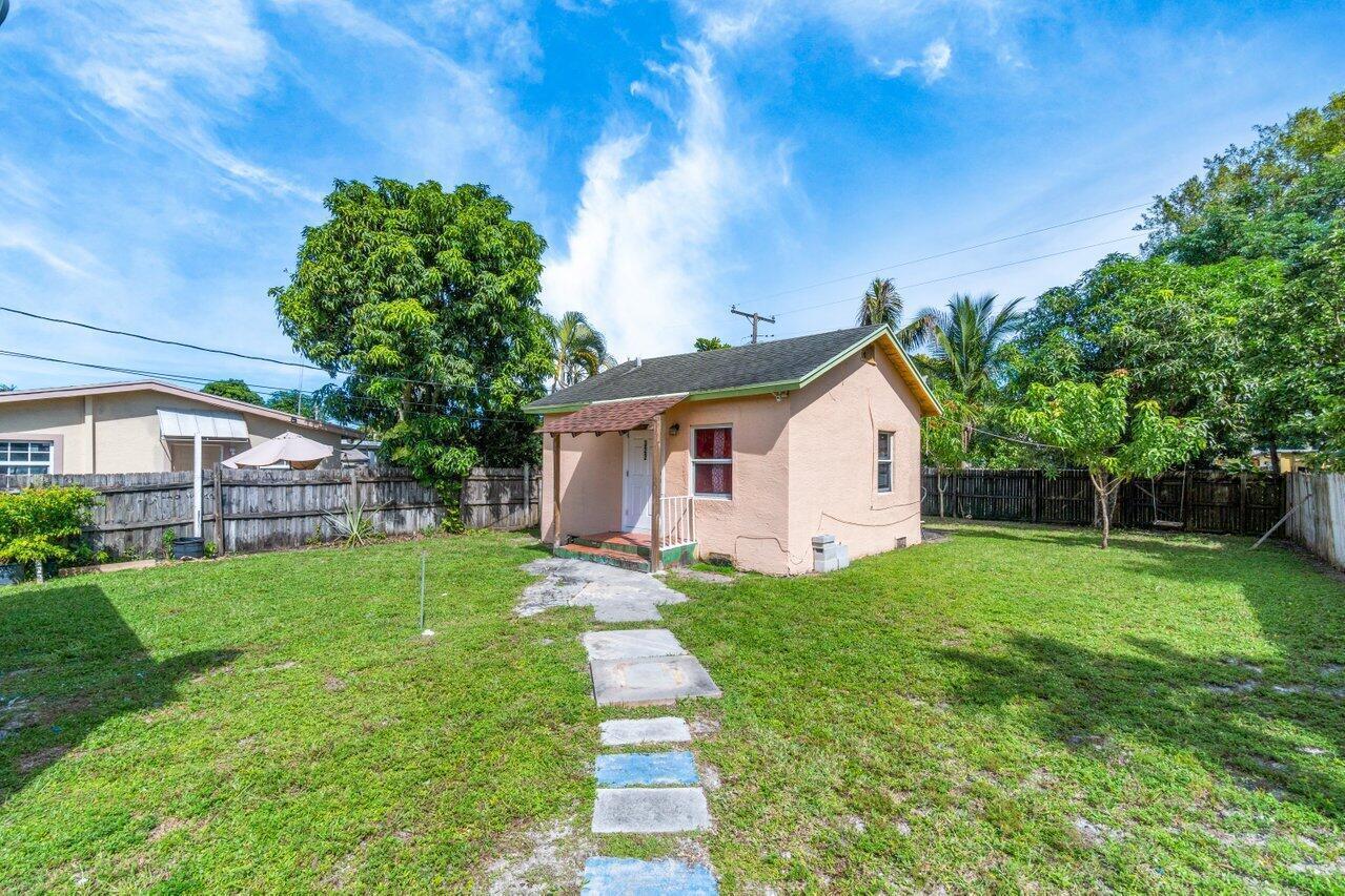 A small, peach-colored house with a front porch sits in a grassy yard — 320 Swain Boulevard, FL 33463, FL
