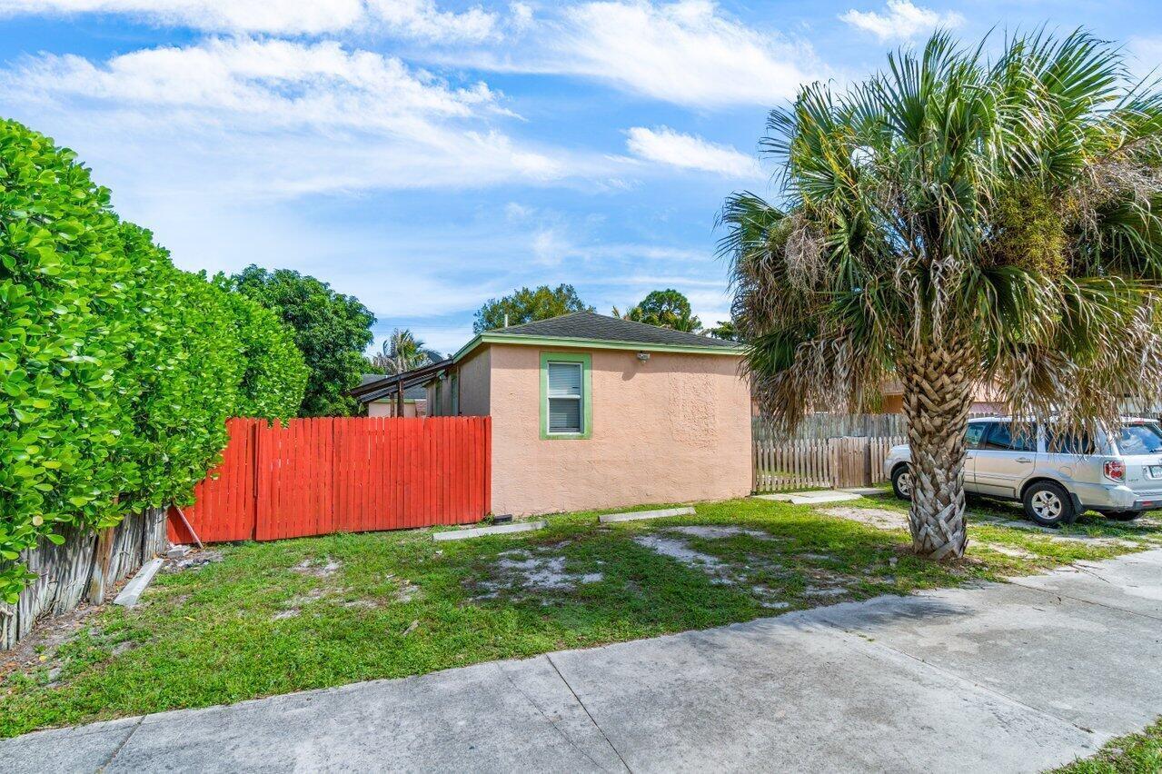 A small, peach-colored house with a red fence and a palm tree in the yard — 320 Swain Boulevard, FL 33463, FL