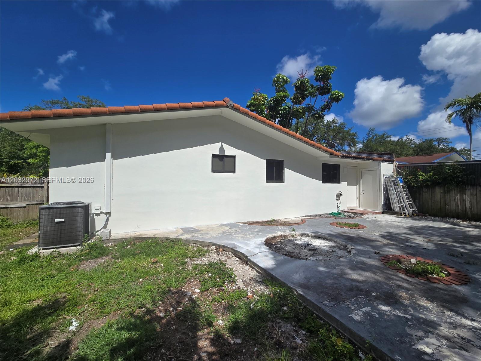 The exterior of a white house features a tiled roof, concrete patio, and AC unit — 13100 NE 3rd Ct # 1, North Miami FL 33161, NORTH MIAMI, FL