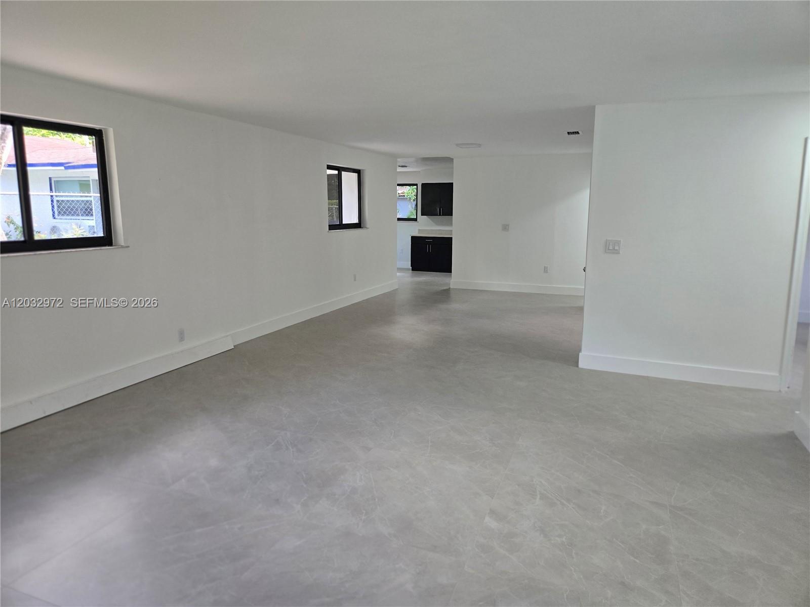 An open-concept living area features light gray tile flooring and white walls — 13100 NE 3rd Ct # 1, North Miami FL 33161, NORTH MIAMI, FL