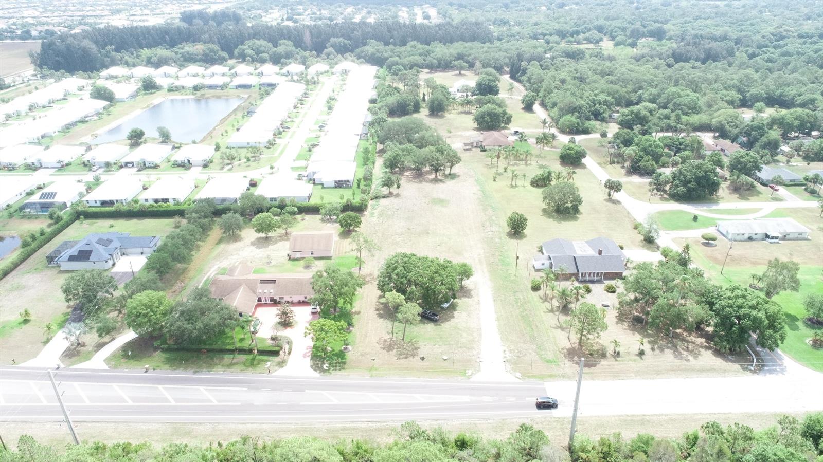 An aerial view shows a residential area with houses, a pond, and open land — 4720 58th Ave Avenue, Vero Beach FL 32967, VERO BEACH, FL