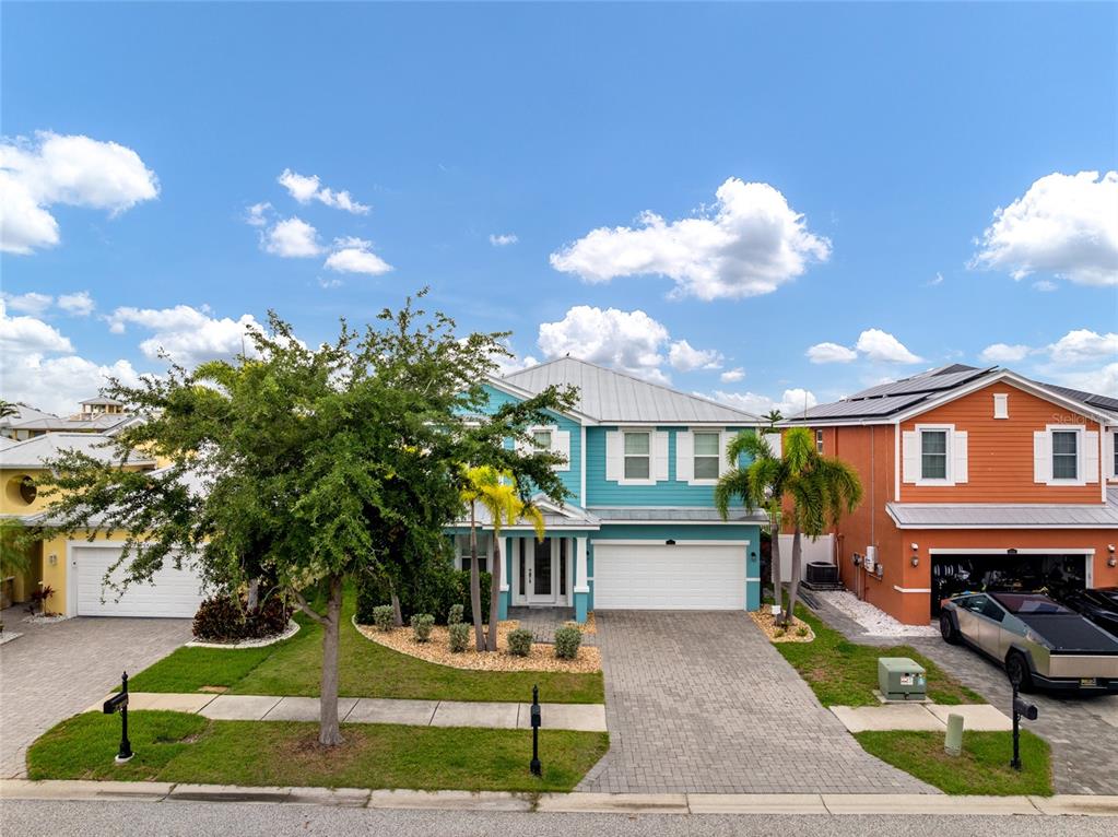 A teal two-story house with a white garage and a paved driveway sits between neighbors — 6412 KEY ISLAND AVENUE, APOLLO BEACH, FL