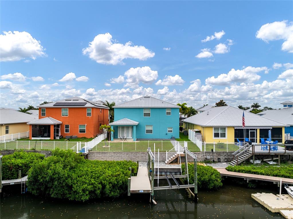 An aerial view shows three colorful waterfront houses with private docks and a canal — 6412 KEY ISLAND AVENUE, APOLLO BEACH, FL