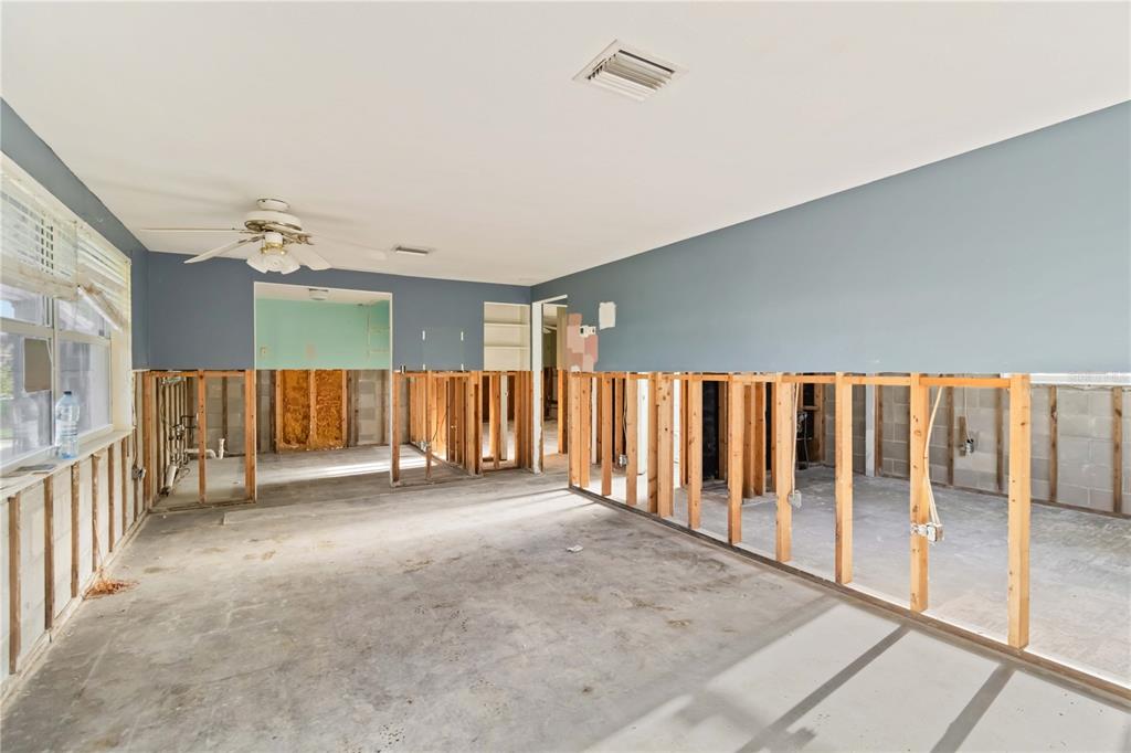 An unfinished room with exposed wall studs, concrete floors, and blue painted upper walls — 1255 S MARYKNOLL ROAD, ENGLEWOOD, FL