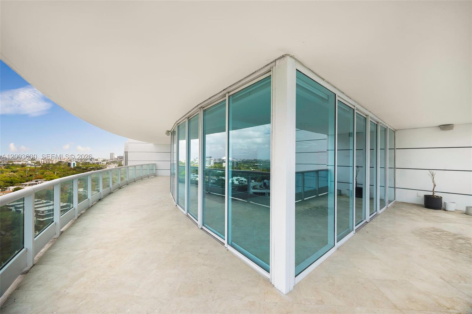 A wide, curved balcony with glass railings and floor-to-ceiling windows wraps around a building corner — 2127 Brickell Ave # 1805, Miami FL 33129, MIAMI, FL