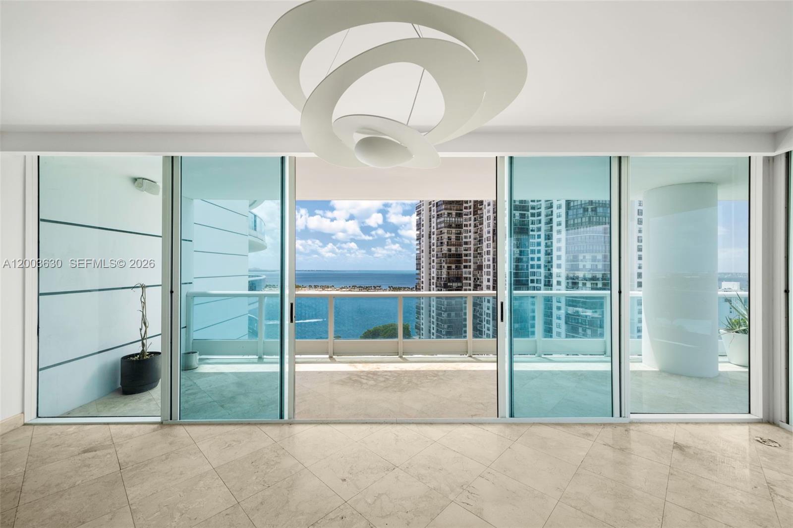An interior room with marble floors features large sliding glass doors opening to a balcony — 2127 Brickell Ave # 1805, Miami FL 33129, MIAMI, FL