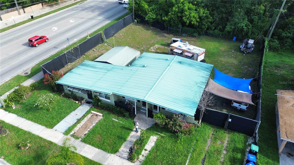 An aerial view shows a house with a green metal roof and a fenced yard — 6923 ANOKA DRIVE, ORLANDO, FL