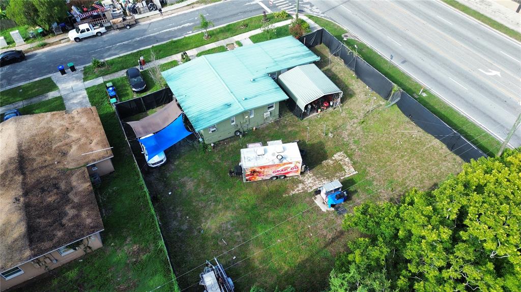 An aerial view shows a house with a green roof, a carport, and a food trailer — 6923 ANOKA DRIVE, ORLANDO, FL