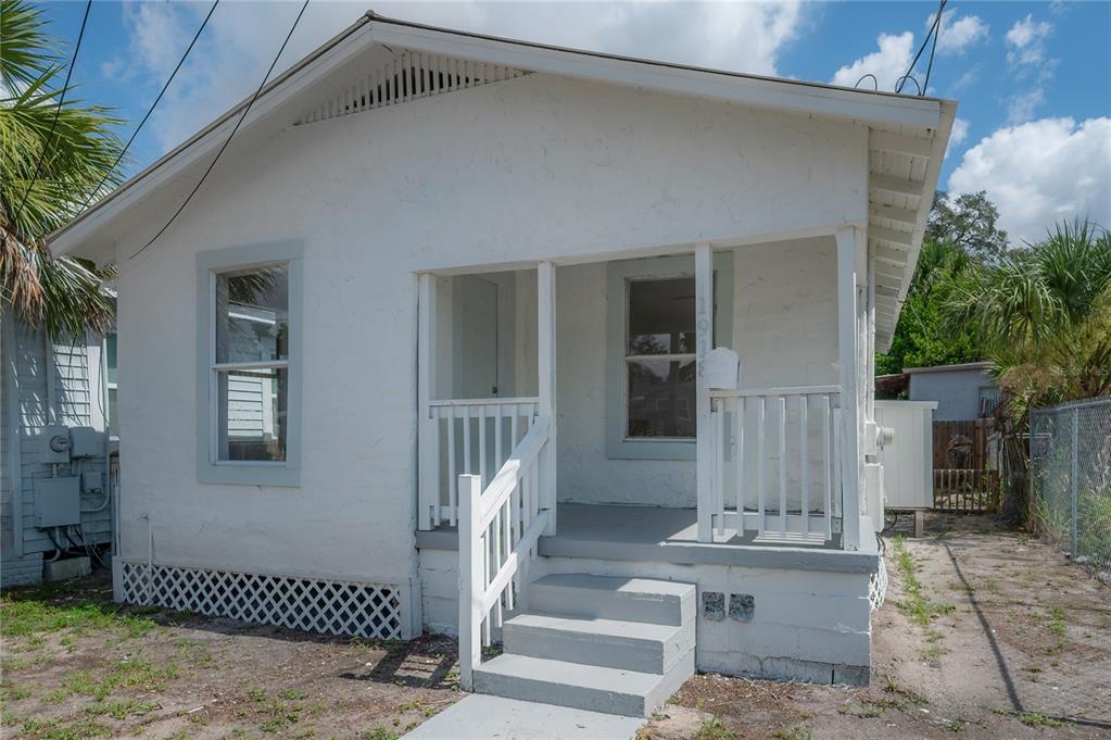 A small, white, single-story house with a front porch, stairs, and lattice skirting — 1918 E 21ST AVENUE, TAMPA, FL