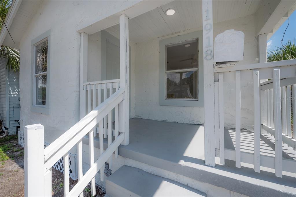 A small, white, single-story house with a front porch, stairs, and lattice skirting — 1918 E 21ST AVENUE, TAMPA, FL