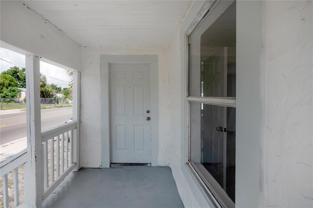 A white house features a front porch with wooden railings and a small staircase — 1918 E 21ST AVENUE, TAMPA, FL