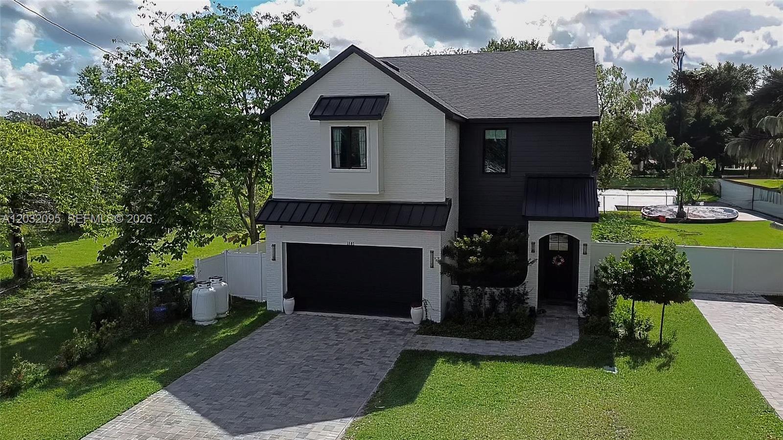 A two-story house with white brick, dark siding, a black garage door, and a paved driveway — 1605 Jessamine Ave, Orlando FL 32806, ORLANDO, FL
