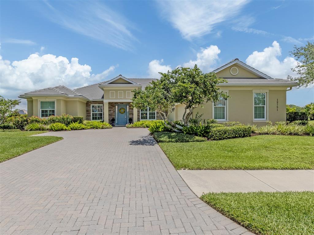 A single-story house with a paved driveway, stone accents, and a blue front door — 19751 COBBLESTONE CIRCLE, VENICE, FL