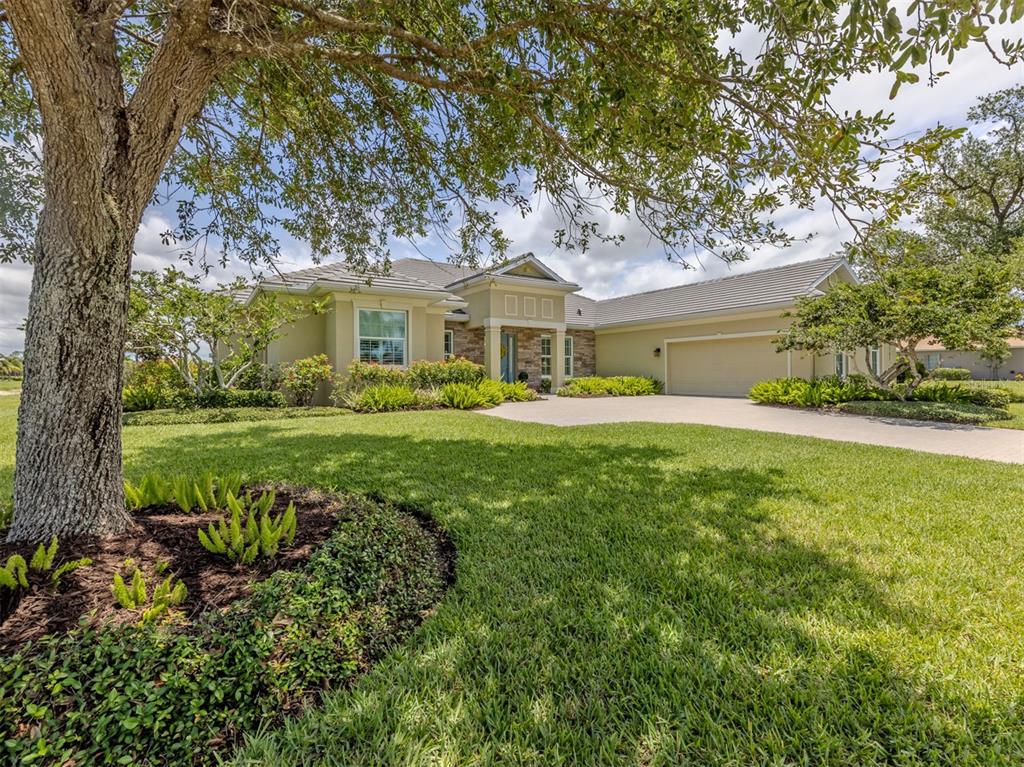A single-story house with a beige exterior, stone accents, and a large front lawn — 19751 COBBLESTONE CIRCLE, VENICE, FL