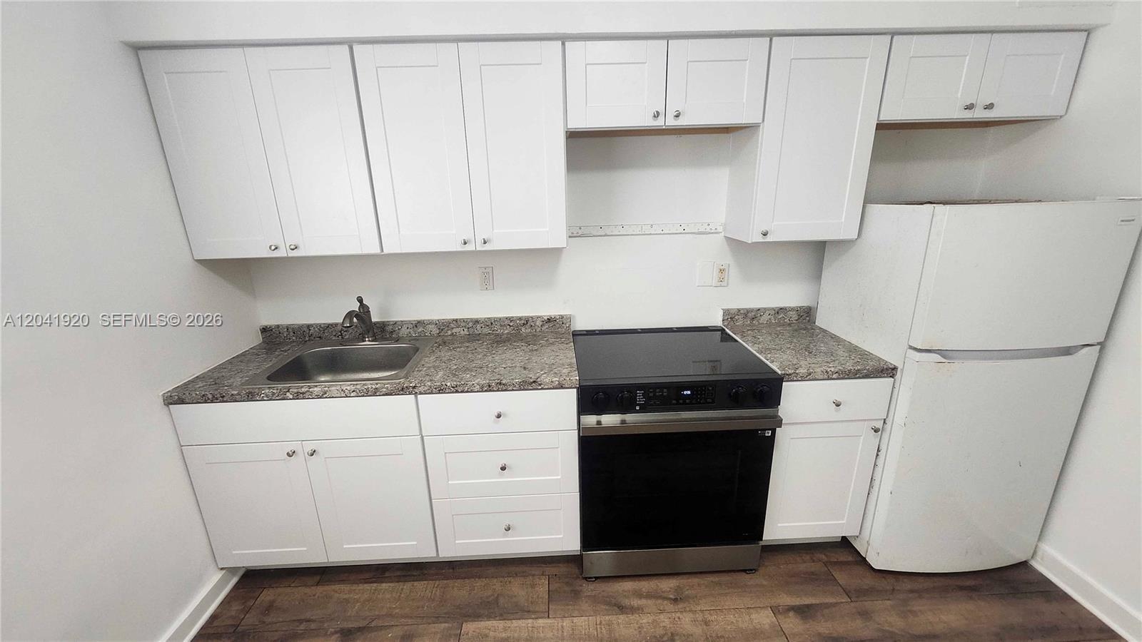 A kitchen features white cabinets, granite countertops, a stainless steel stove, and a white refrigerator — 111 NW 152nd St # 11, Miami FL 33169, MIAMI, FL