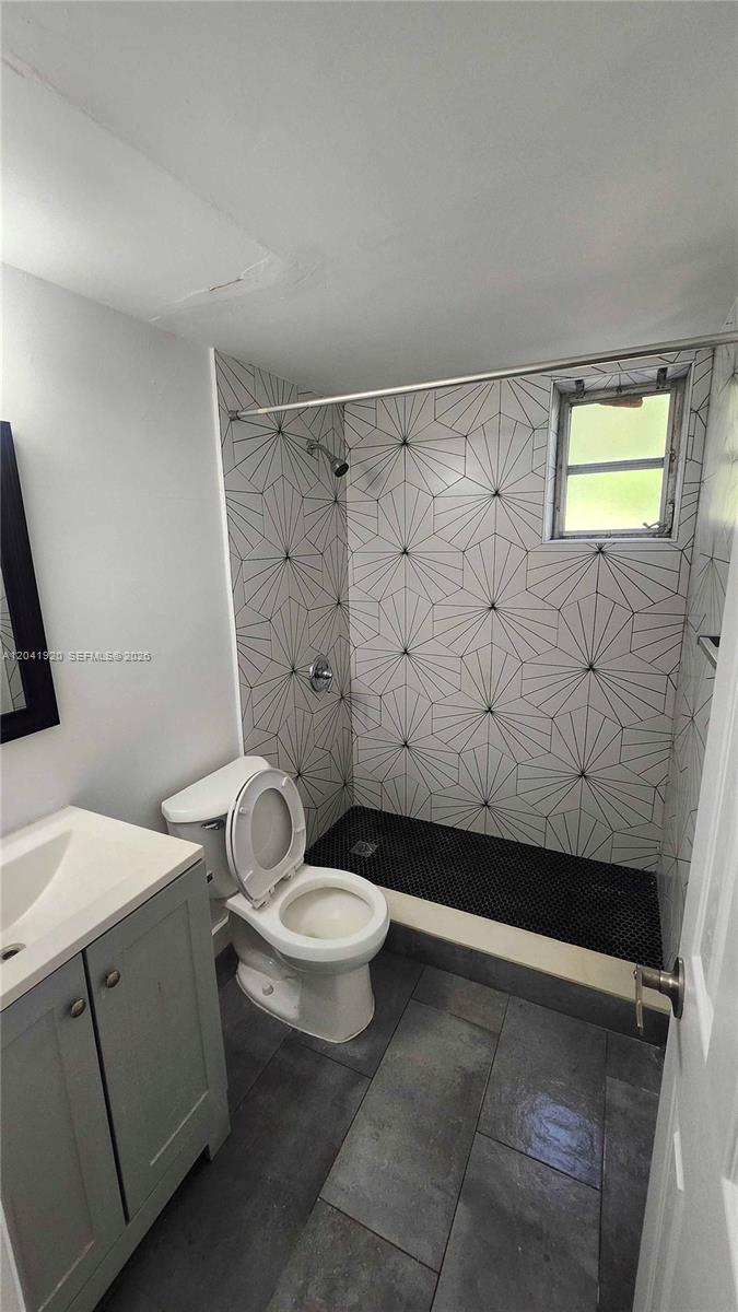 A bathroom features a walk-in shower with geometric tile, a toilet, and a vanity — 111 NW 152nd St # 11, Miami FL 33169, MIAMI, FL