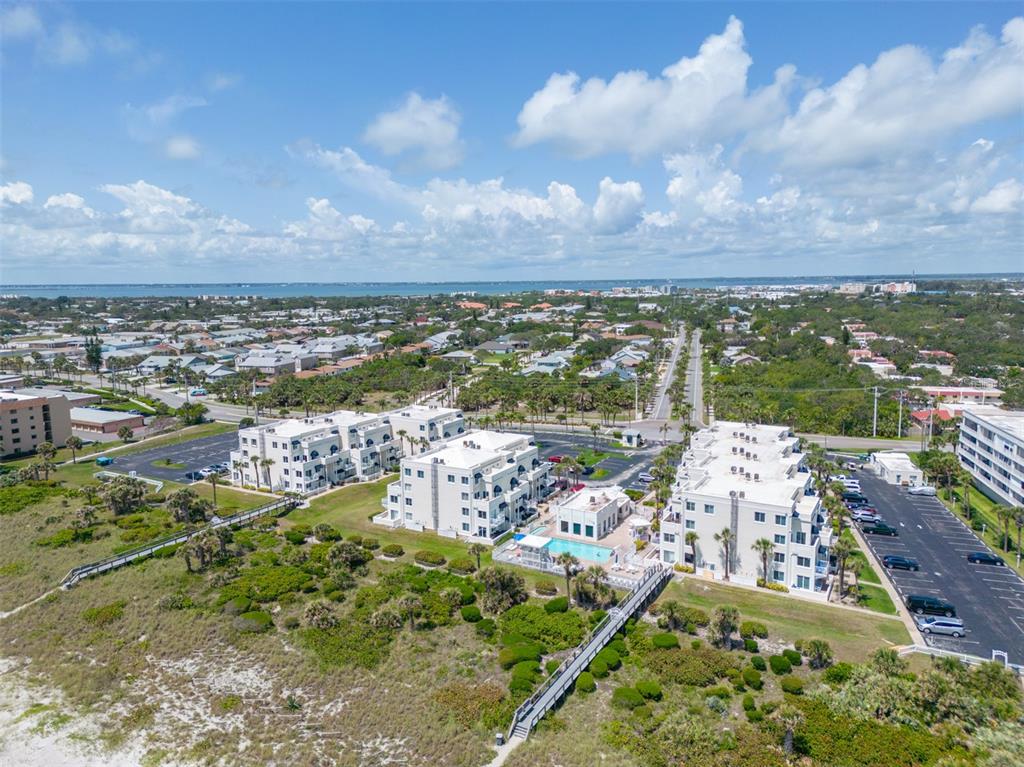 An aerial view of beachfront condominium buildings with a swimming pool and parking lots — 8600 RIDGEWOOD AVENUE UNIT 1311, CAPE CANAVERAL, FL